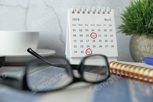 Preview: Close-up of desk with calendar, glasses, and plant showcasing March 2019 important dates