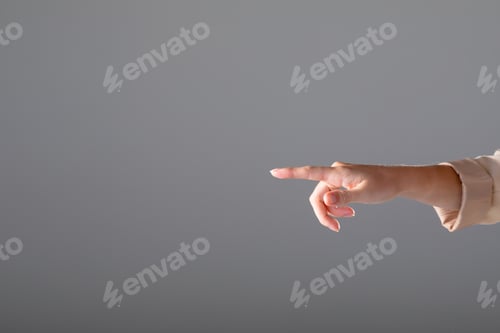 Preview: Midsection of caucasian businesswoman pointing with her finger, isolated on grey background