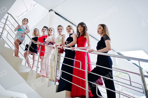 Preview: Group of outstandingly beautiful ladies in dresses posing on the stairs.