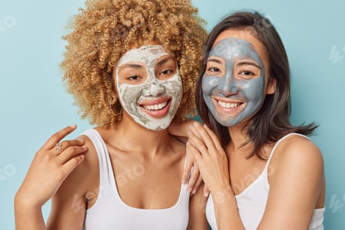 Preview: Cheerful women apply beauty clay mask for reducing blackheads smile gladfully stand closely to each