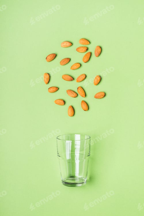 Preview: Almonds and glass on green background. Health care, diet and nutrition concept