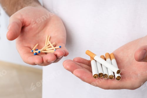 Preview: Cigarettes and matches in male hands on a light background