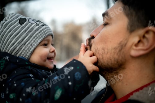 Preview: Dad hugs and kisses the baby tightly. Dad and son are walking outside in the park