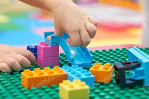 Preview: child playing and building with colorful plastic bricks table. Early learning and development.