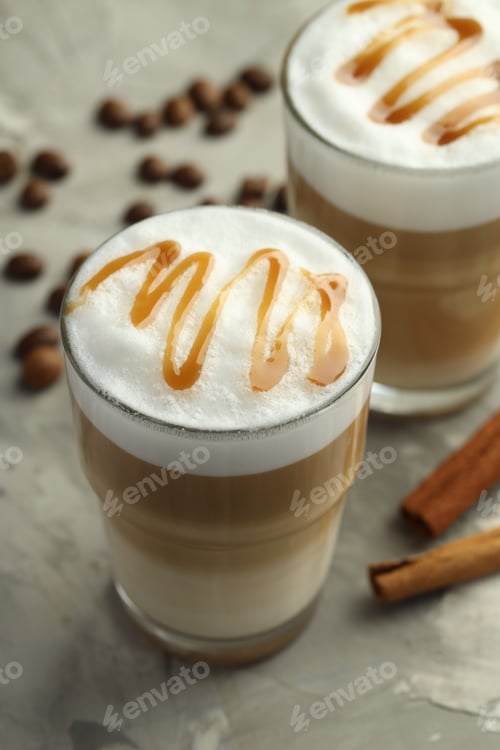 Preview: Tasty latte macchiato in glasses, coffee beans and cinnamon on grey table, closeup