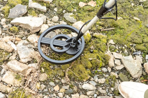 Preview: A man with a metal detector on the shore of a reservoir.
