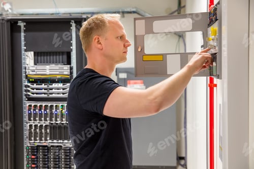 Preview: Confident Male Technician Checking Fire Panel In Datacenter