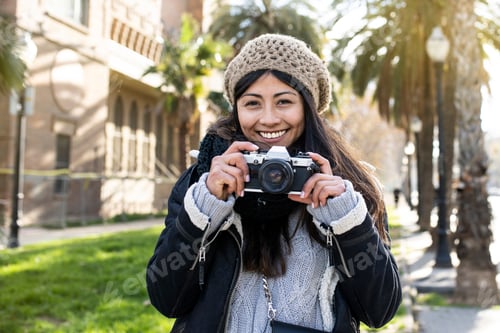 Preview: smiling woman traveler holding a camera at the city in holidays - relaxation, tourism concept
