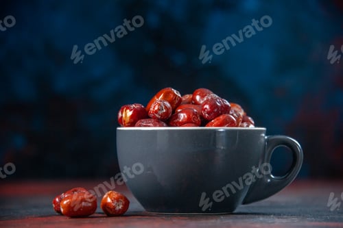 Preview: Front close view of fresh raw silverberry fruits inside and outside of a gray cup on mix colors