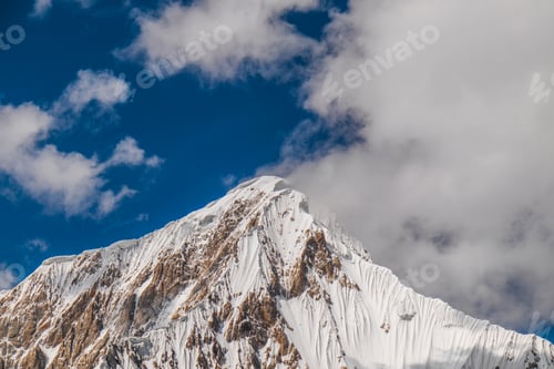 Preview: Snowcapped mountain peak under a cloudy blue sky