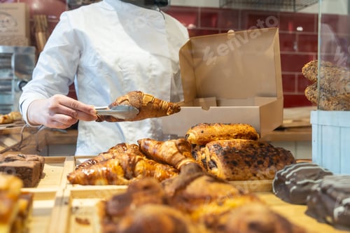 Preview: Baker serving fresh croissant taking pastry from display