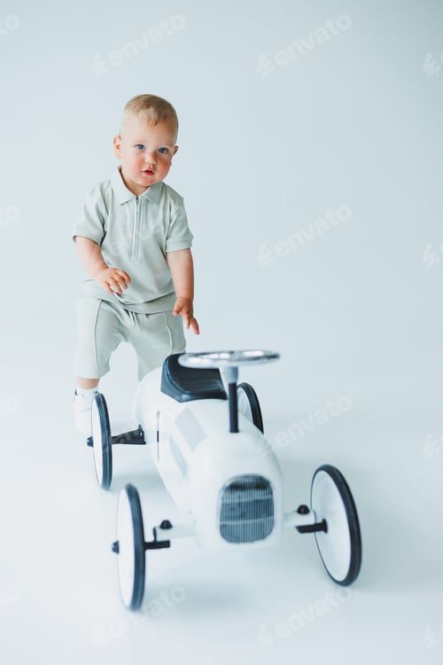 Preview: An absolutely adorable toddler is having a wonderful time playing on a stylish toy car within
