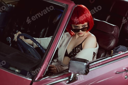 Preview: high angle view of beautiful woman in sunglasses, bra and trench coat driving classic car and