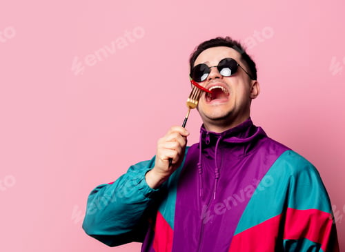 Preview: Style guy in glasses with chili pepper on a fork on pink background