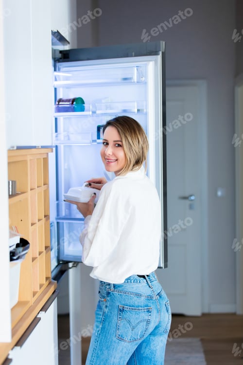 Preview: woman in white shirt and blue jeans stay near refrigerator