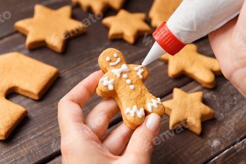 Preview: Confectioner decorating gingerman with royal icing, closeup
