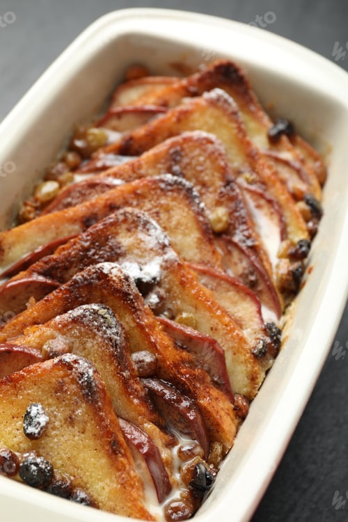 Preview: Freshly baked bread pudding in baking dish on grey table, closeup