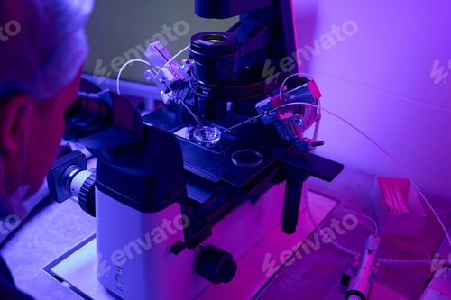 Preview: Biolaboratory worker looking at microscope doing cells biopsy