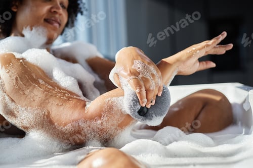 Preview: Hands of Black Woman Rubbing Skin with Bath Sponge Washing Body Indoors