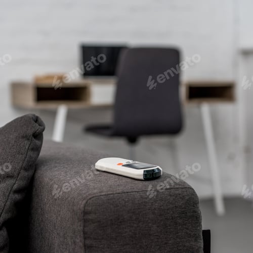 Preview: close-up shot of air conditioner remote control lying on sofa with workplace on background
