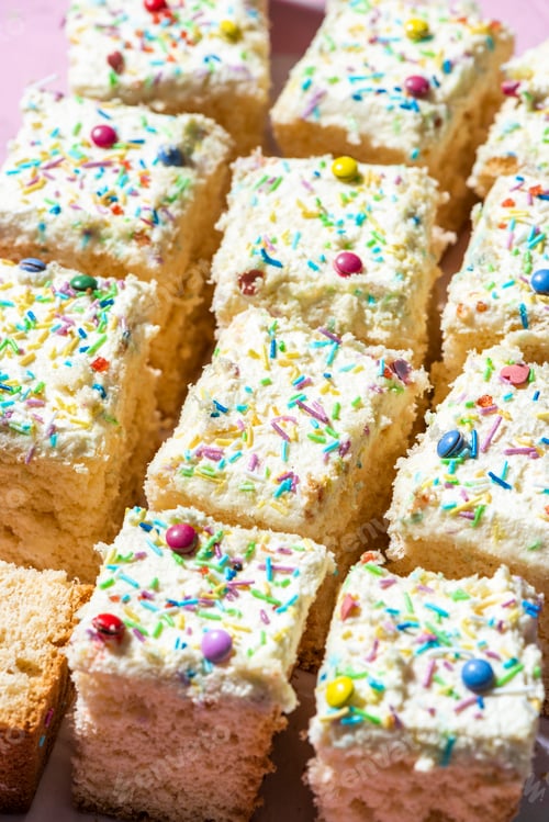 Preview: Sliced Sponge Cake DEcorated With Cream and Sprinkles. Closeup View
