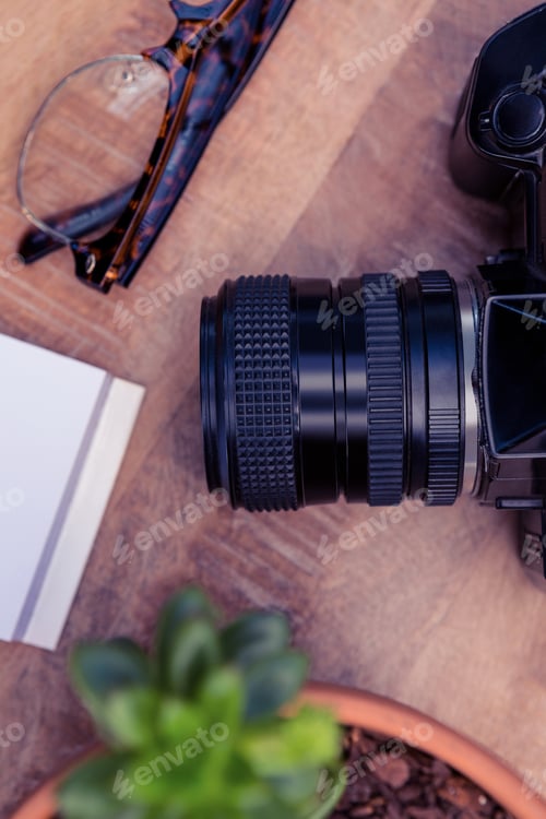 Preview: Camera by eye glasses on wooden table in office