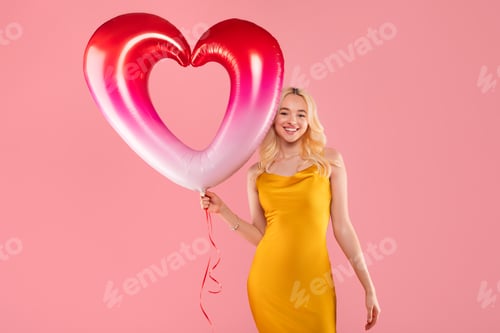 Preview: Happy woman with a heart balloon on pink backdrop