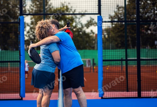 Preview: Mixed adult couple celebrate winning the point in padel on outdoor court.