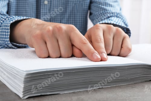 Preview: Blind person reading book written in Braille at table, closeup