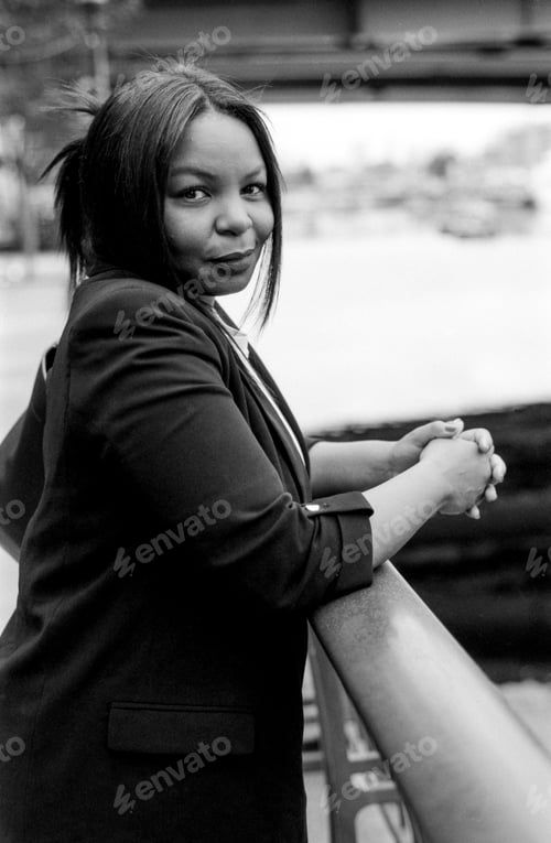 Preview: Confident businesswoman leaning on railing in urban setting, grainy monochrome portrait