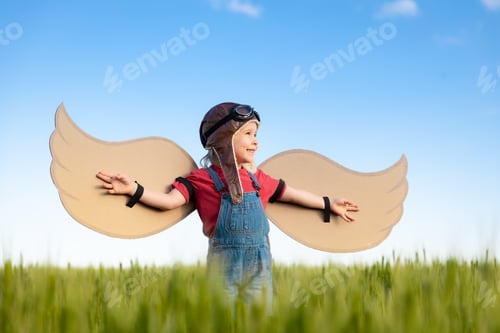 Preview: Happy child with cardboard wings playing outdoor in summer