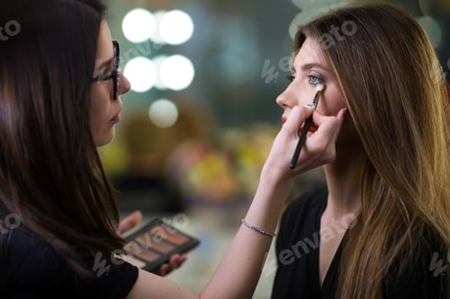 Preview: Professional makeup artist working with beautiful young woman. Fashionable Female Model.