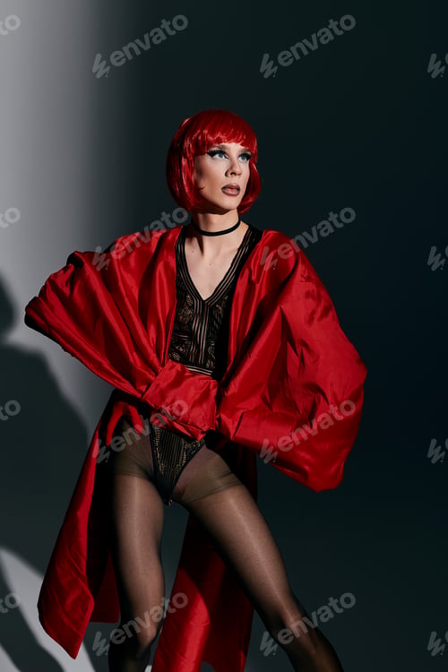 Preview: Striking Young Drag Queen in Bold Red Outfit Posing Gracefully Against a Dramatic Backdrop