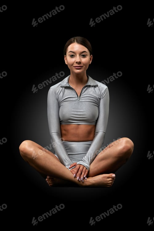 Preview: Beautiful sporty fitness girl doing yoga sitting in lotus position on a dark background. Yoga