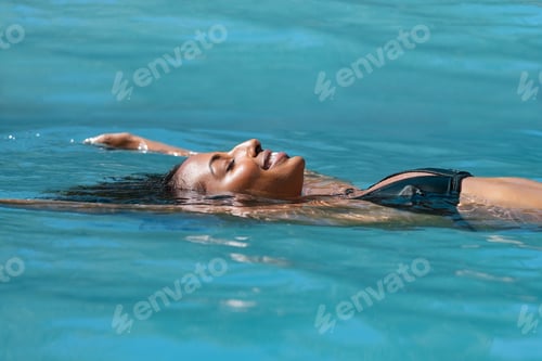 Preview: Relaxed woman floating in swimming pool