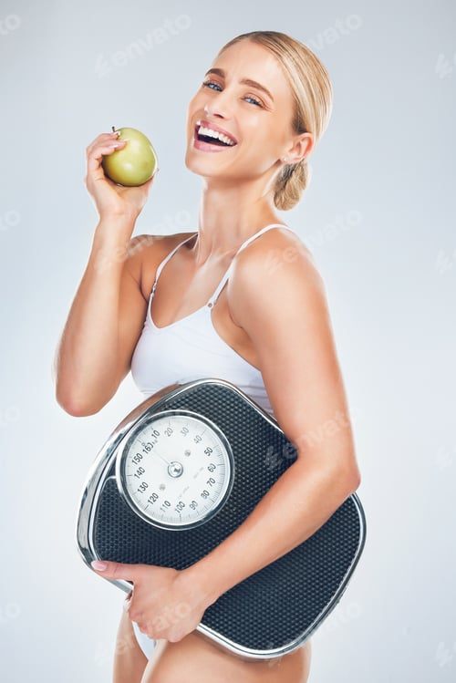 Vista previa: Apple, dieta y mujer con una báscula para perder peso, entrenando y sonriendo sobre un fondo gris de estudio