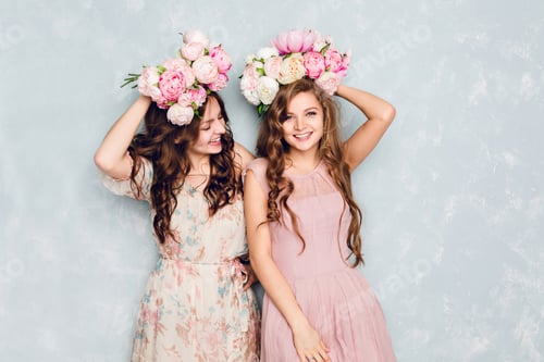 Preview: Two beautiful girls stand in a studio, play silly and have circlets of flowers on their heads. They
