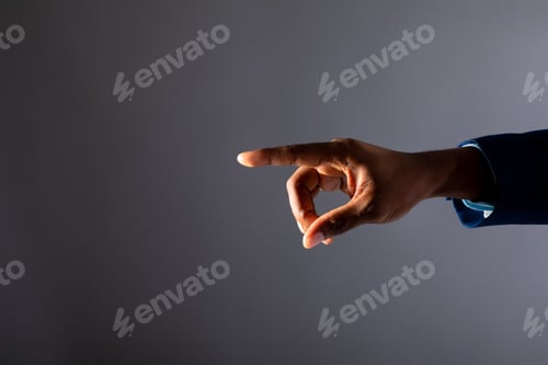 Preview: Mid section of african american businessman touching invisible screen against grey background
