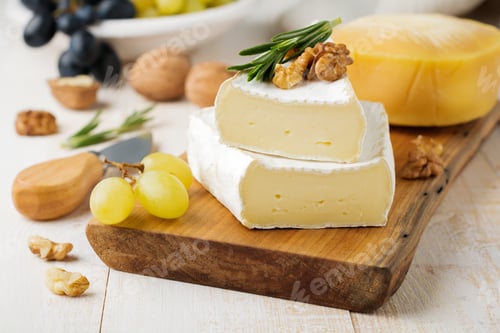 Preview: Stack Camembert cheese with grapes, walnuts and basil on gray light concrete or stone background. Se