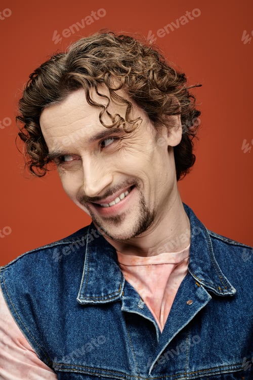Preview: Handsome Man Smiling Against a Vibrant Orange Backdrop in Urban Setting