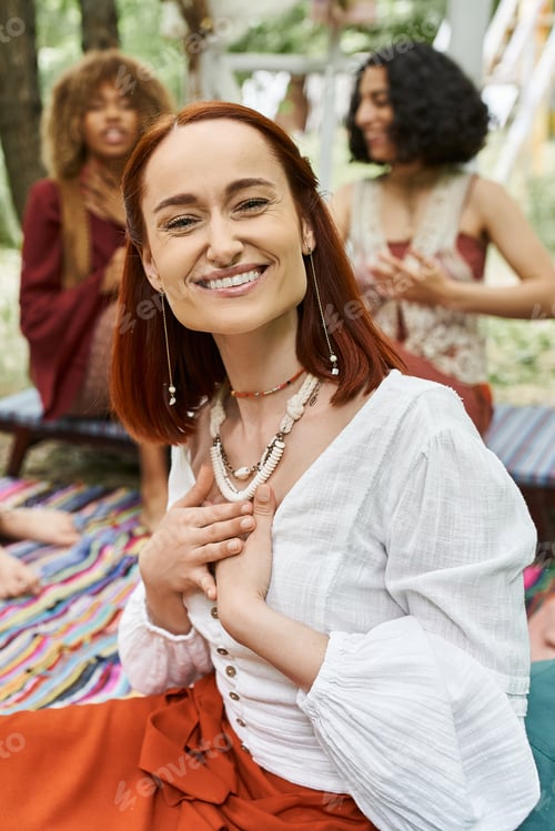 Preview: portrait of cheerful woman sitting near blurred interracial friends outdoors in retreat center