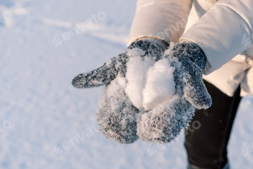 Preview: Woman holds snow in blue mittens. Winter holiday