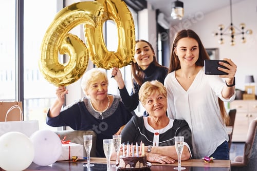 Preview: Balloons with number 60. Senior woman with family and friends celebrating a birthday indoors