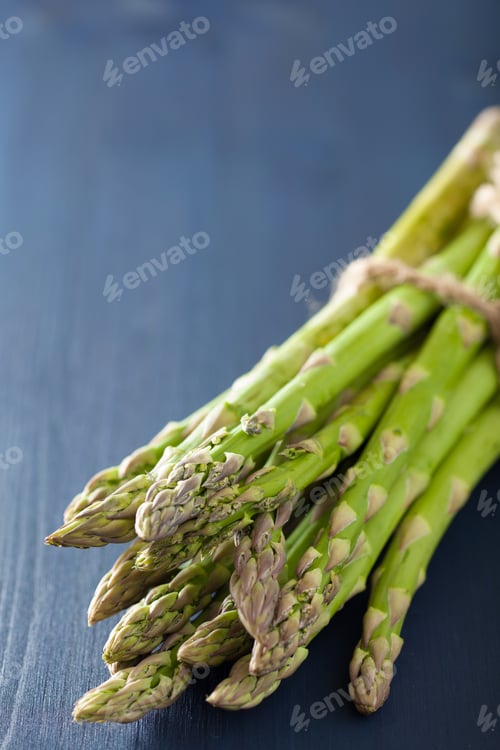 Preview: bunch of fresh asparagus on blue background