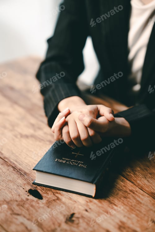 Preview: Cropped view of young woman praying with bible on table Confession concept Pray and talk with God