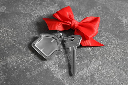 Preview: House key with trinket and bow on grey background