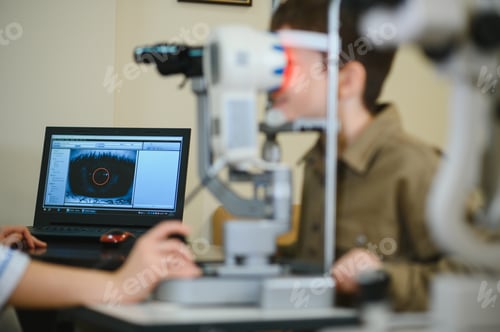 Preview: Ophthalmologist checking child's vision with modern equipment in clinic