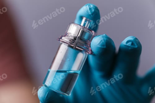 Preview: Medical vial in the hands of a doctor with gloves