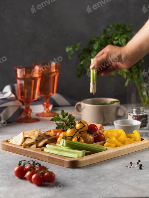 Preview: Mix of fresh vegetables on a wooden plate. Vegetarian snack. Pieces of pepper, celery with hummus