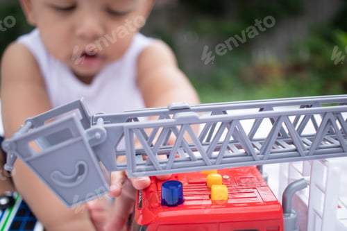 Preview: Cute Toddler Playing with a Toy Firetruck Outdoors